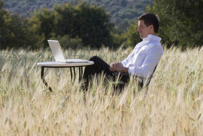 Business man in wheat field working on computer